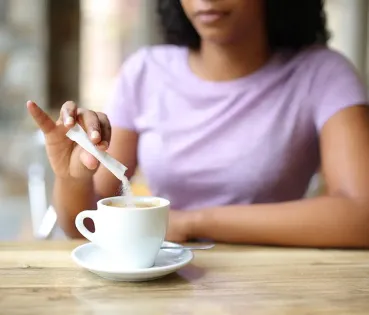 Woman adding sugar in the coffe. 