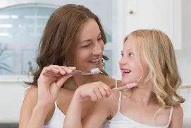 Mother and daughter brushing their teeth
