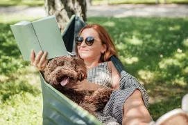 Mujer leyendo en un jardín en la sombra, con precaución a la exposición solar.