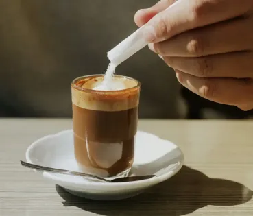 Dona afegint sucre al cafè.