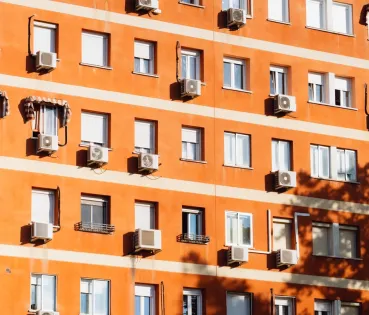 Façade of a building with multiple air conditioning units installed.