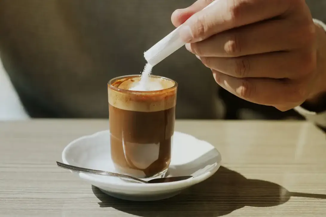 Woman adding sugar in the coffe.
